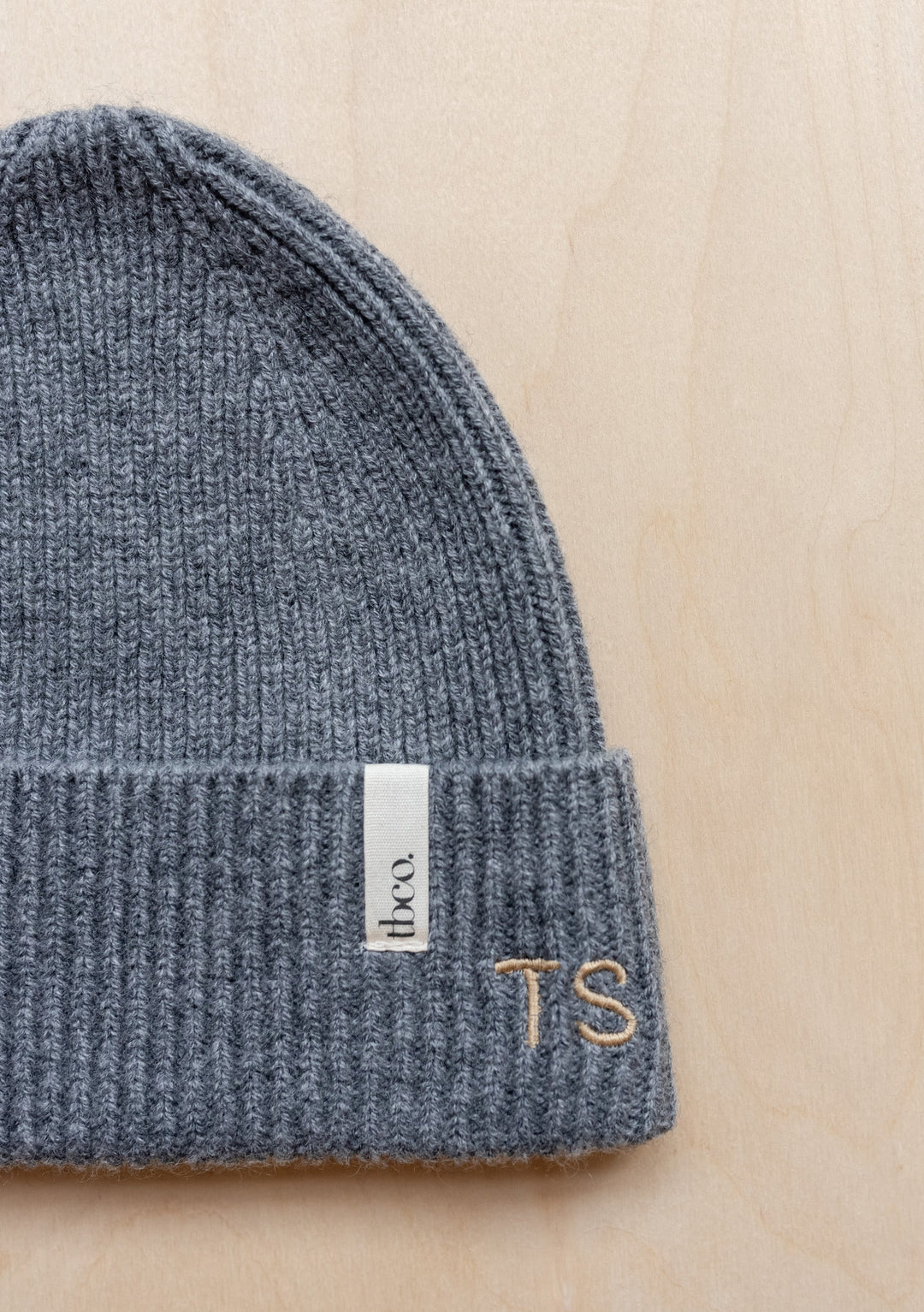 Close-up view of TBCo Merino Wool Baby Beanie in pistachio green, showing ribbed knit texture and brand label detail