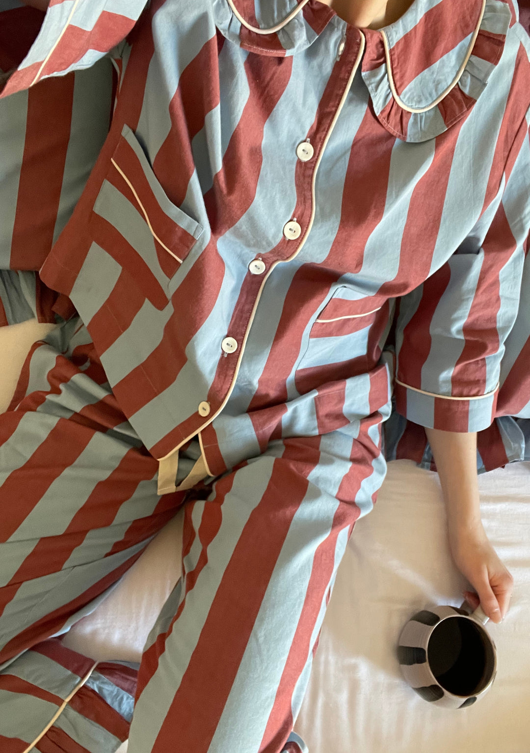 TBCo Cotton Pyjamas in blue and burgundy stripes with ruffled collar, shown with morning coffee on white bedding