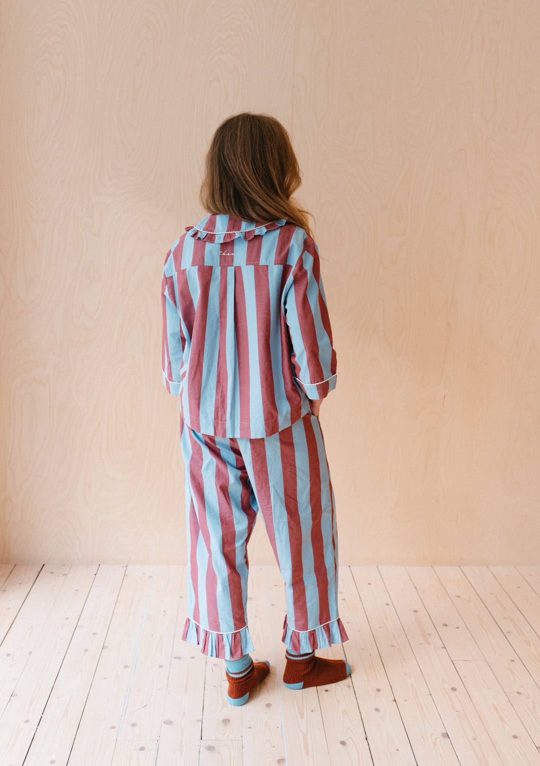 Model wearing TBCo Cotton Pyjamas in Blue and Red Stripe, showcasing ruffled design and cropped sleeves from back view