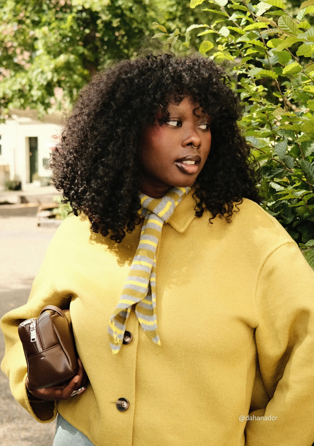 Woman wearing a TBCo Merino Wool Neck Tie in Green Stripe paired with a yellow jacket outdoors in soft daylight