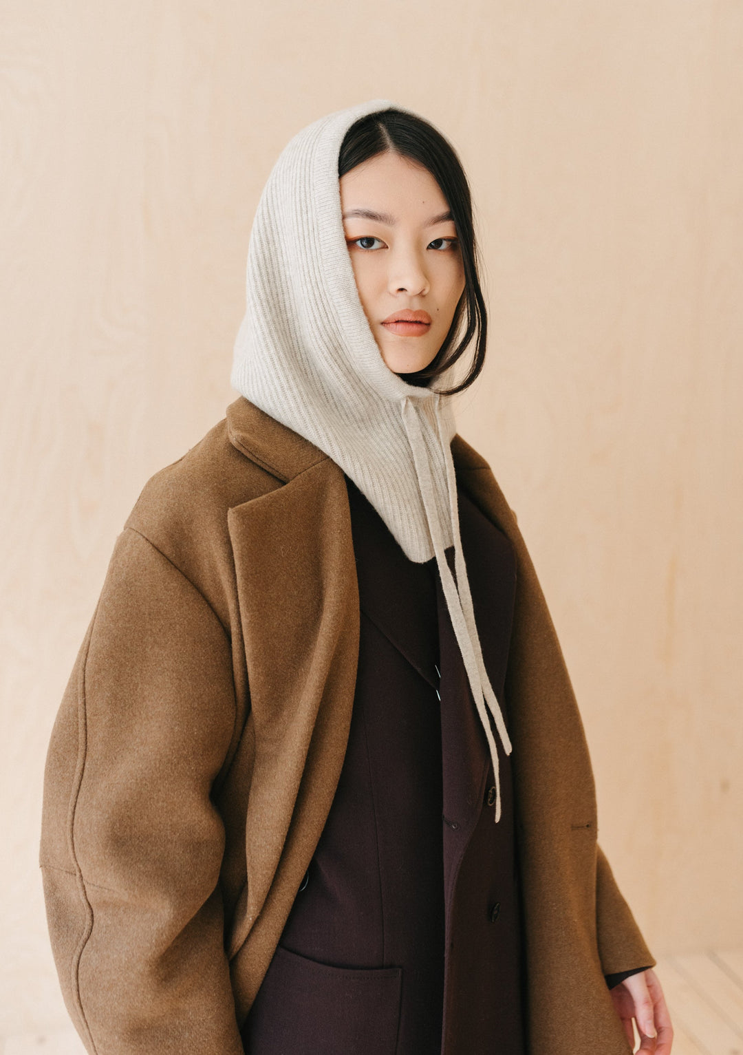 TBCo Merino Hood in Oatmeal Melange shown on model wearing brown coat, demonstrating hood's versatile winter styling