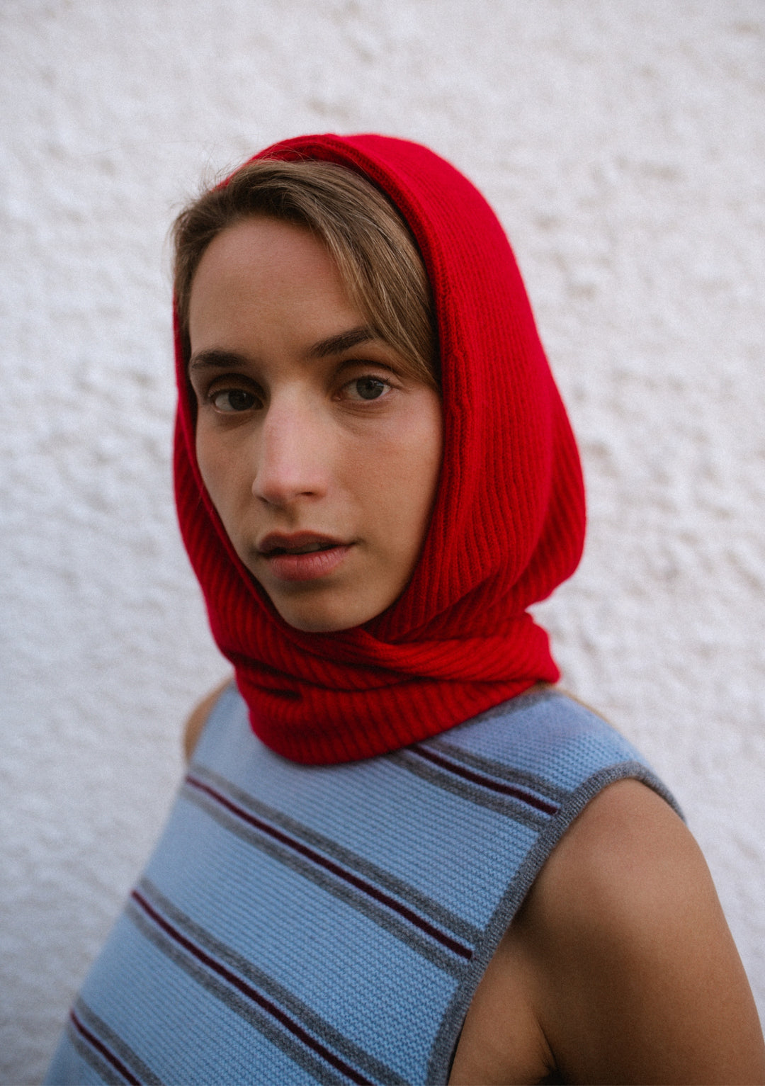 Woman wearing a TBCo Merino Hood in Red, a soft breathable wool hood and scarf with long ties wrapped around the neck.