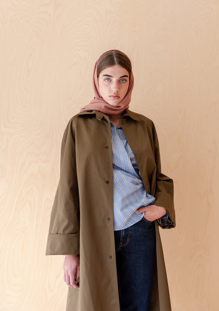 Model wearing TBCo Lambswool Scarf in Blush styled with coat and striped shirt against wood background