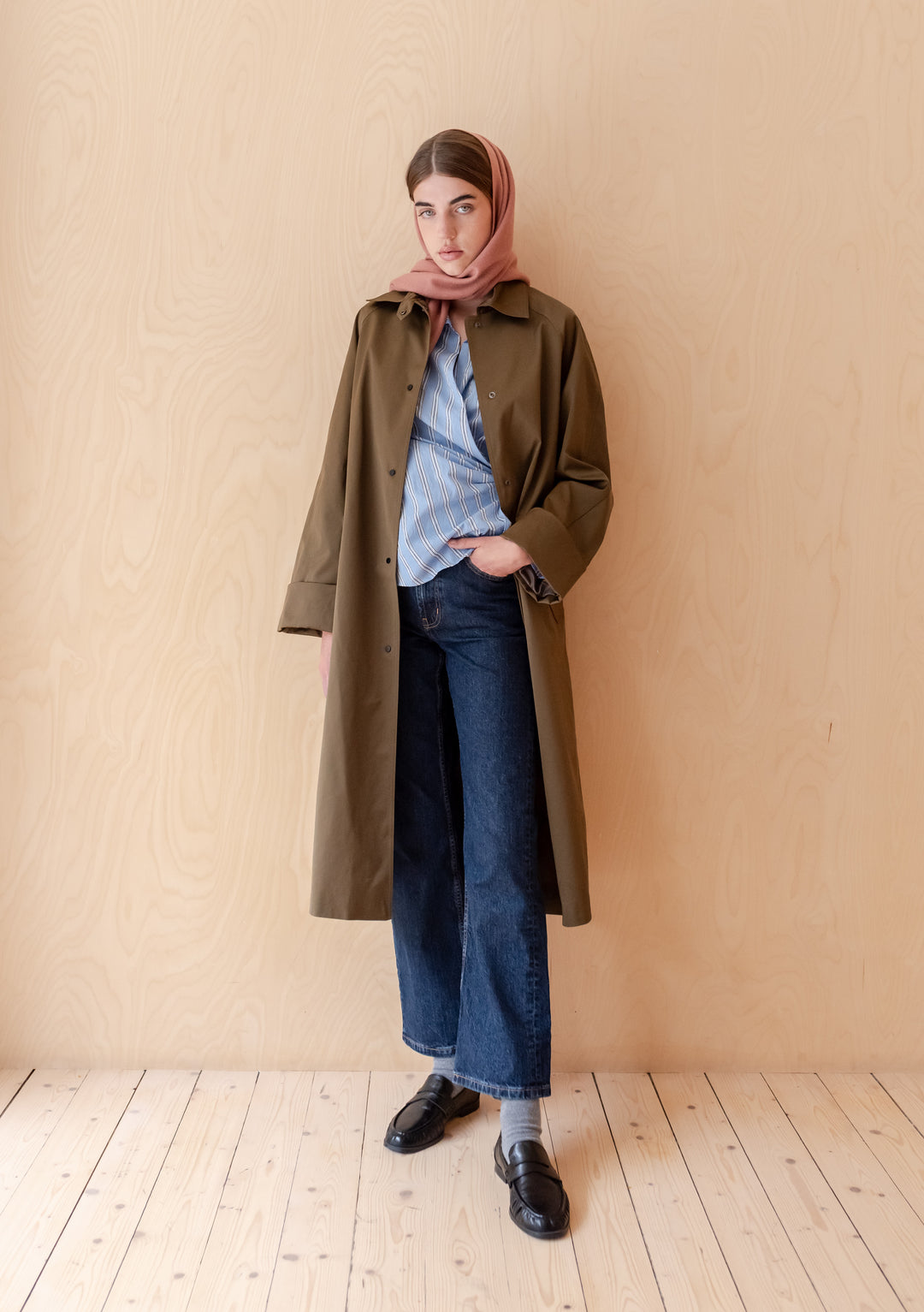 Model wearing TBCo Lambswool Scarf in Blush styled with long coat, shirt, jeans, and loafers in minimalist setting