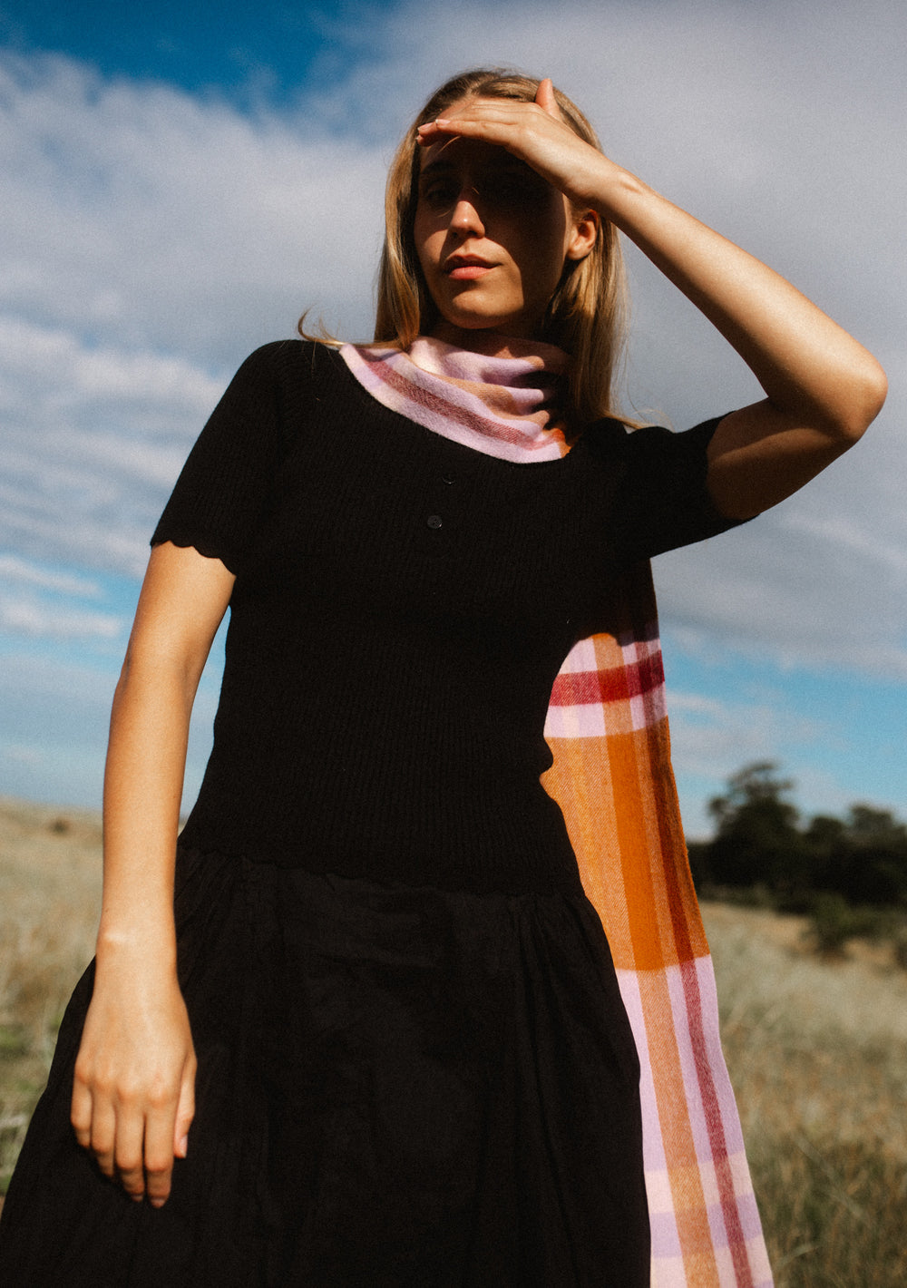 Woman wearing TBCo Lambswool Skinny Scarf in Lilac Modern Tartan over black top outdoors on sunny day