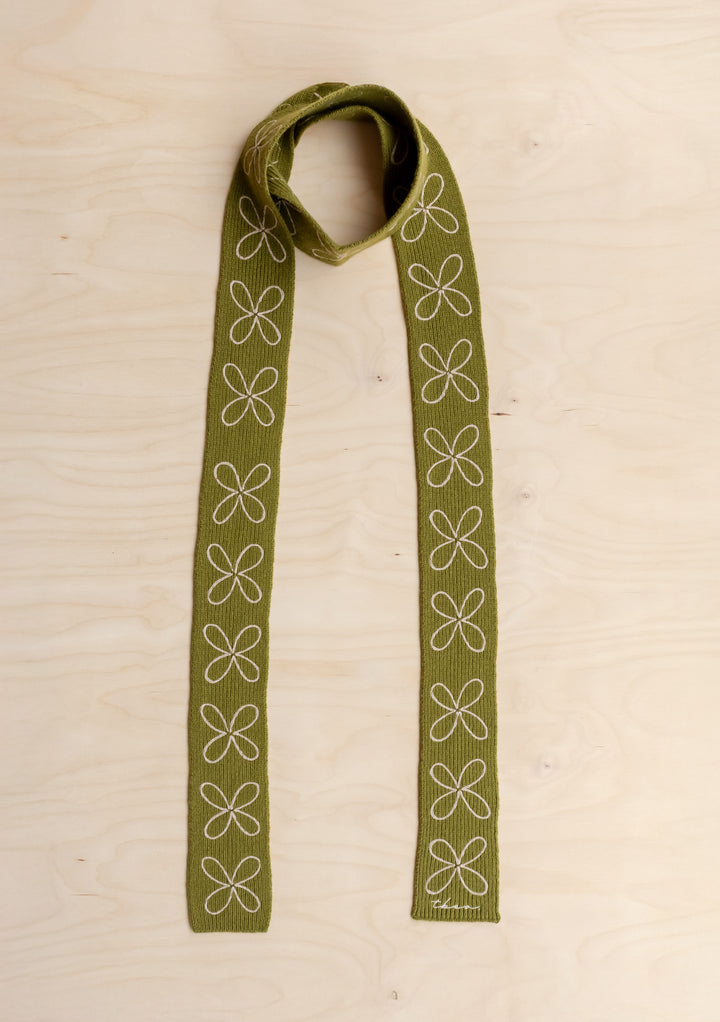 TBCo Merino Wool Skinny Scarf in Green Flora on a wooden background.