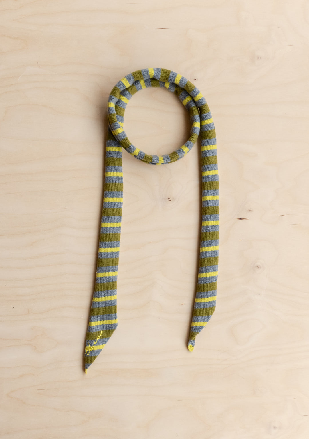 TBCo Merino Wool Neck Tie in Green Stripe scarf on a wooden background.