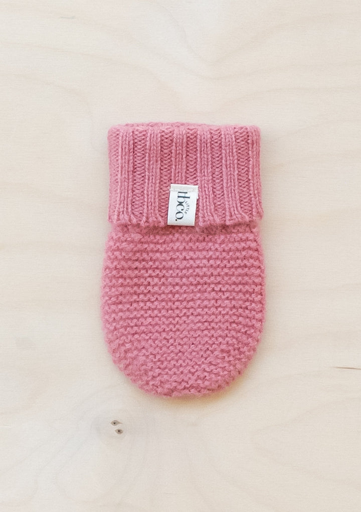 TBCo Merino Wool Baby Mittens in Rose, knitted with ribbed cuff and brand label, displayed on cream background