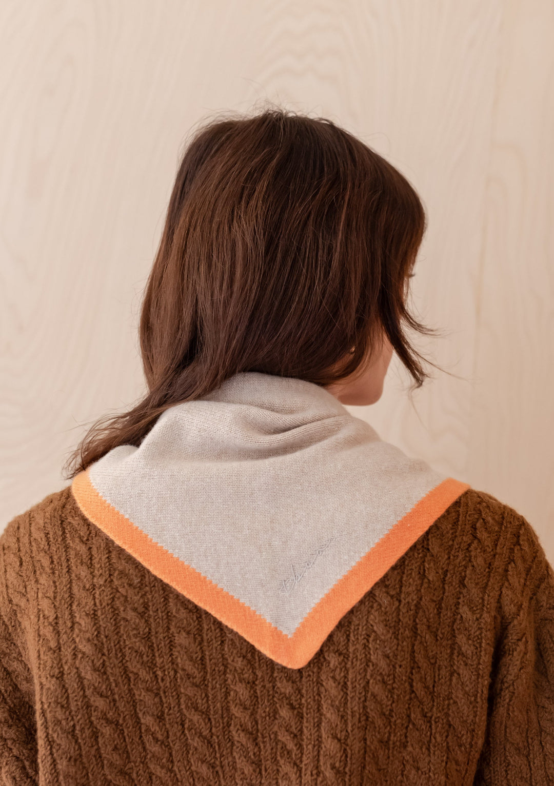 TBCo Merino Triangle Scarf in camel with apricot edging shown draped over brown cable knit jumper, back view styling