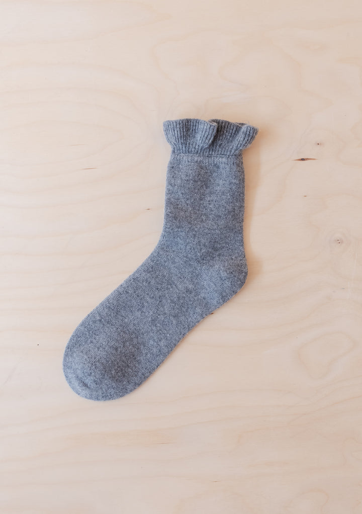 Single Merino Wool Socks in Charcoal Frilly by TBCo laid flat on light wood background with ruffled edge detail