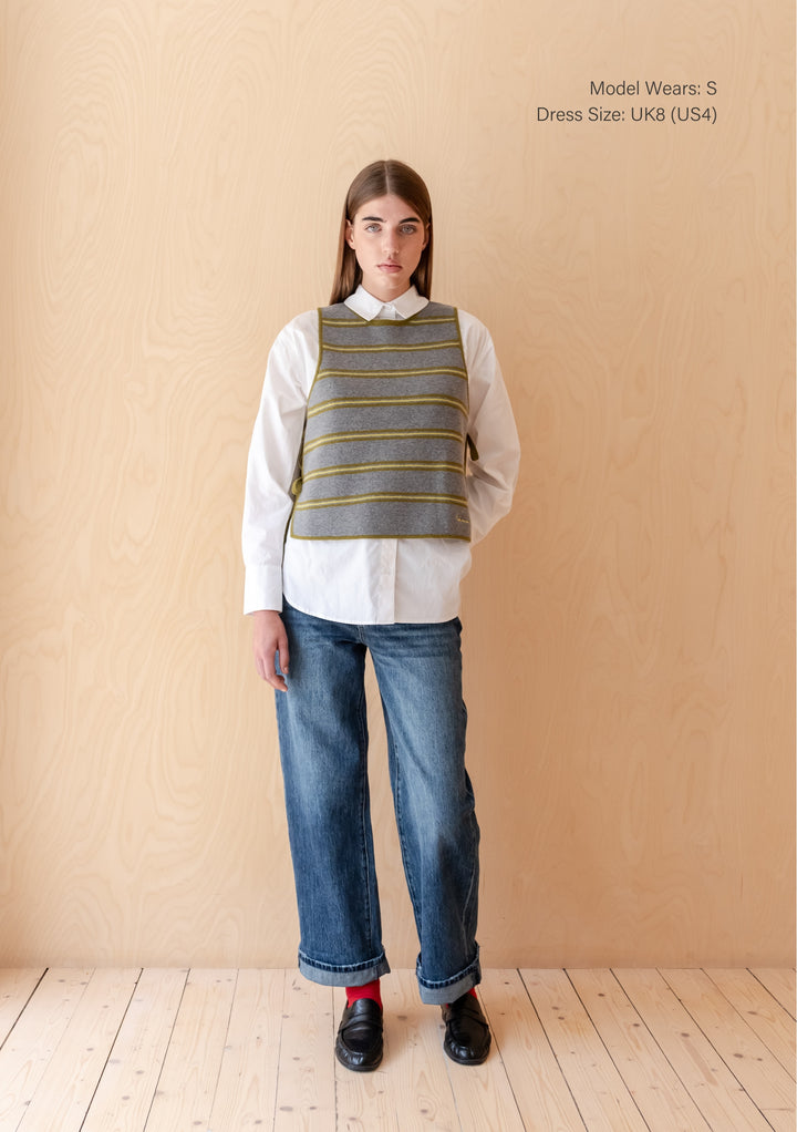 Model wearing TBCo Merino Wool Tie Vest in Green Stripe over white shirt with jeans and black loafers indoors