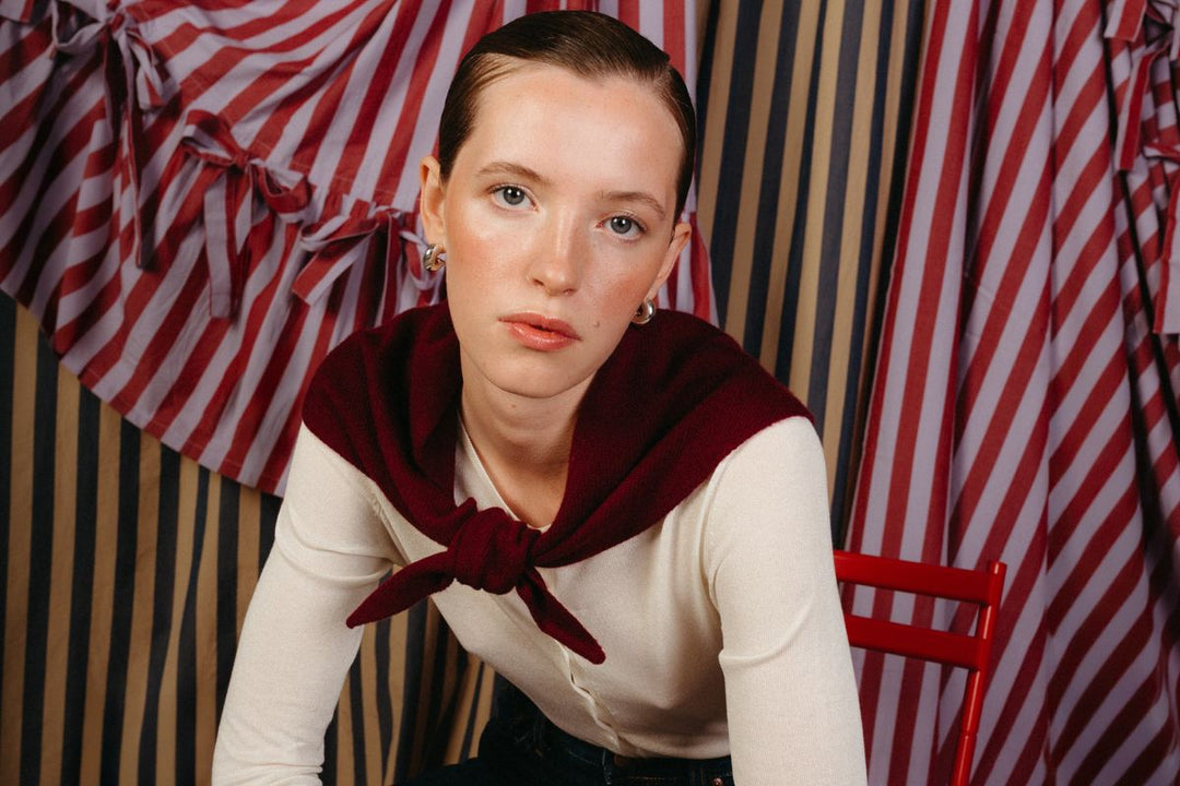 Model wears a TBCo merino wool triangle scarf in lilac and rust stripe.