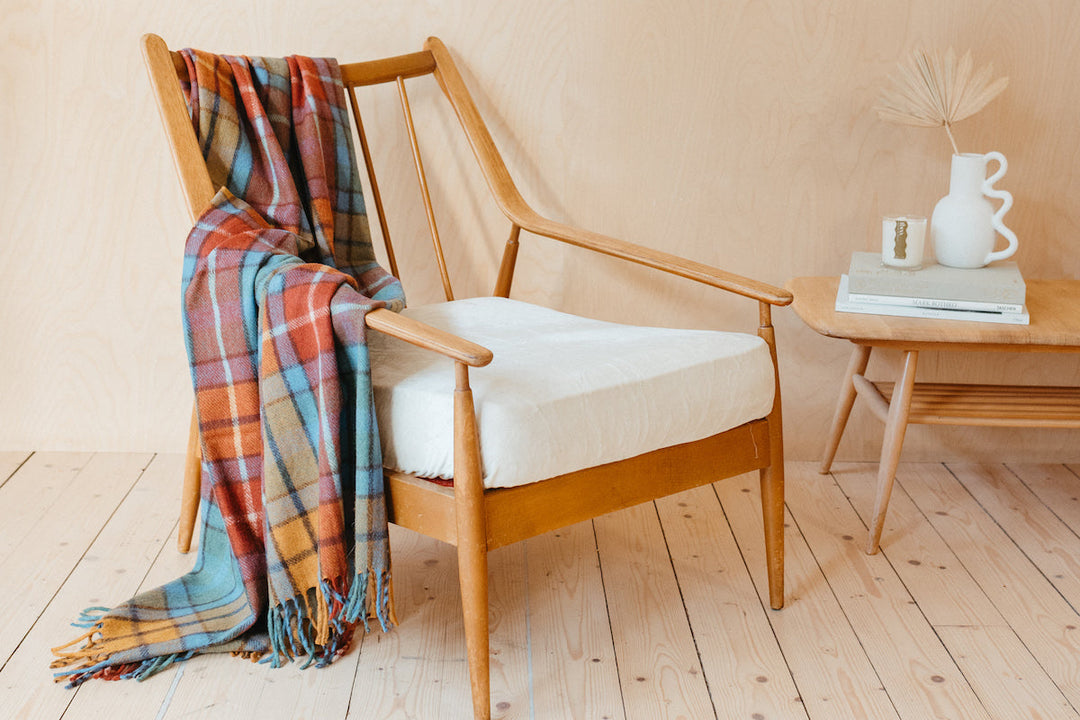 A TBCo recycled wool blanket in buchanan antique tartan draped across a wooden chair.