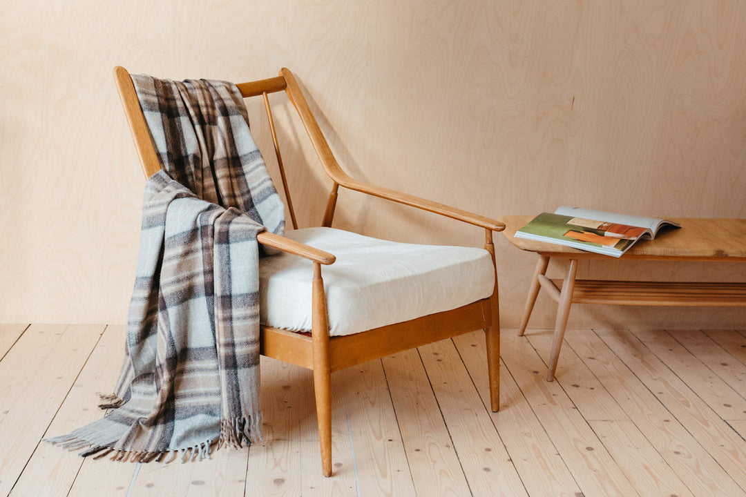 A TBCo lambswool blanket in Mackellar Tartan, draped over a wooden armchair.