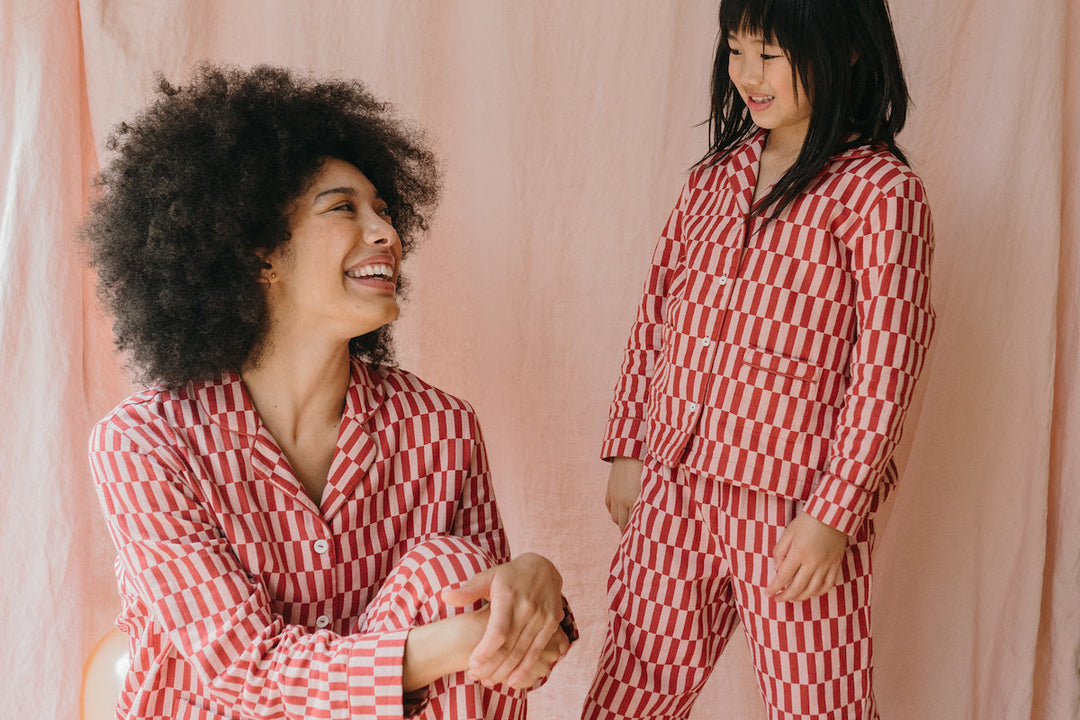 A mother and daughter wearing matching TBCo pyjamas in pink checkerboard.