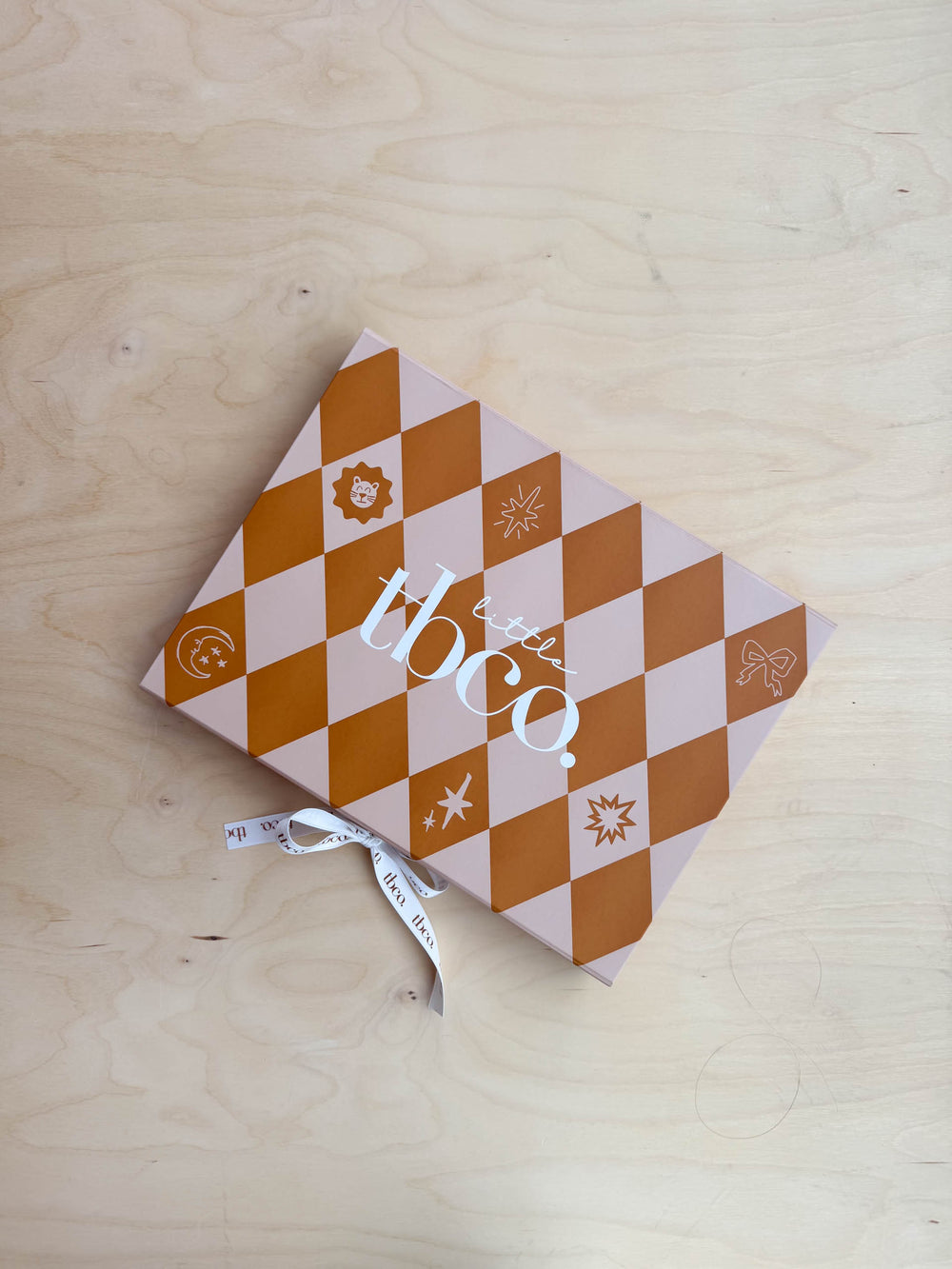 Portrait shot of TBCo Baby Gift Box gallery position 3 with orange check design and ribbon on wooden surface