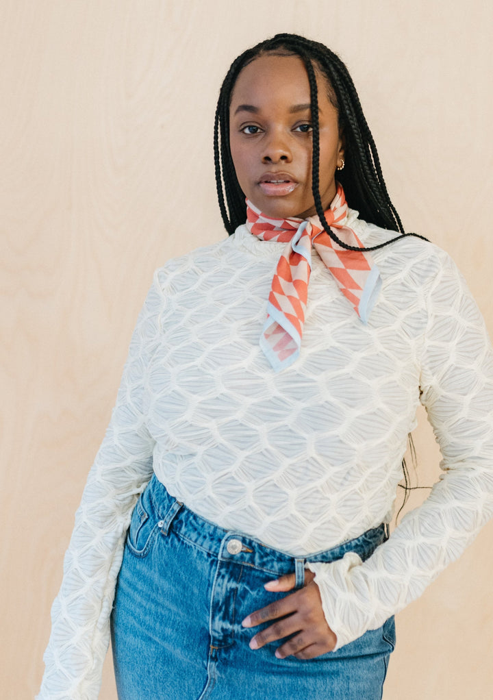 Model in portrait wearing TBCo Sample Sale Cotton Square Scarf in Apricot Checkerboard styled around neck, gallery position one