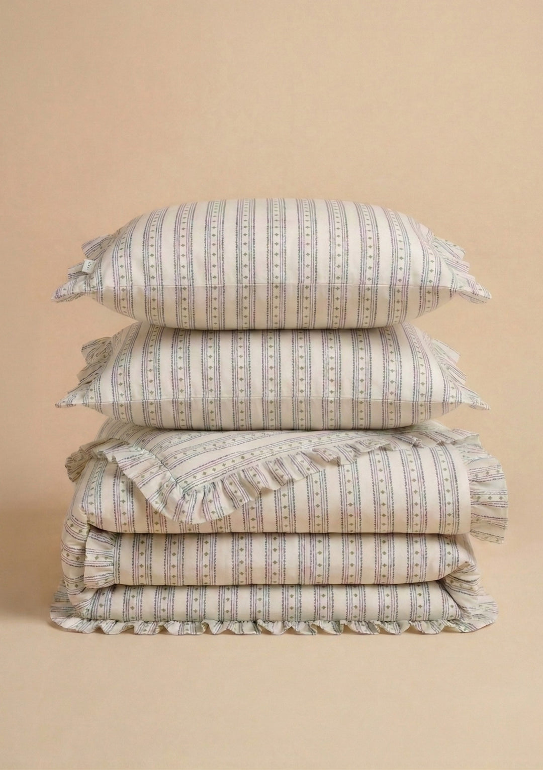Pair of Cotton Pillowcases in Navy Ditsy Floral by TBCo stacked with matching cotton bedding on beige background