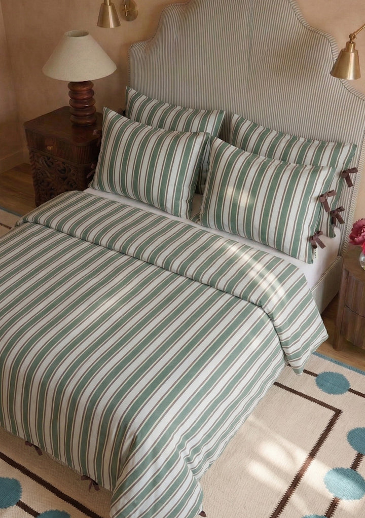 Pair of Cotton Pillowcases in Blue Stripe by TBCo with soft blue and white stripes and brown tie bow accents on cosy bed setting