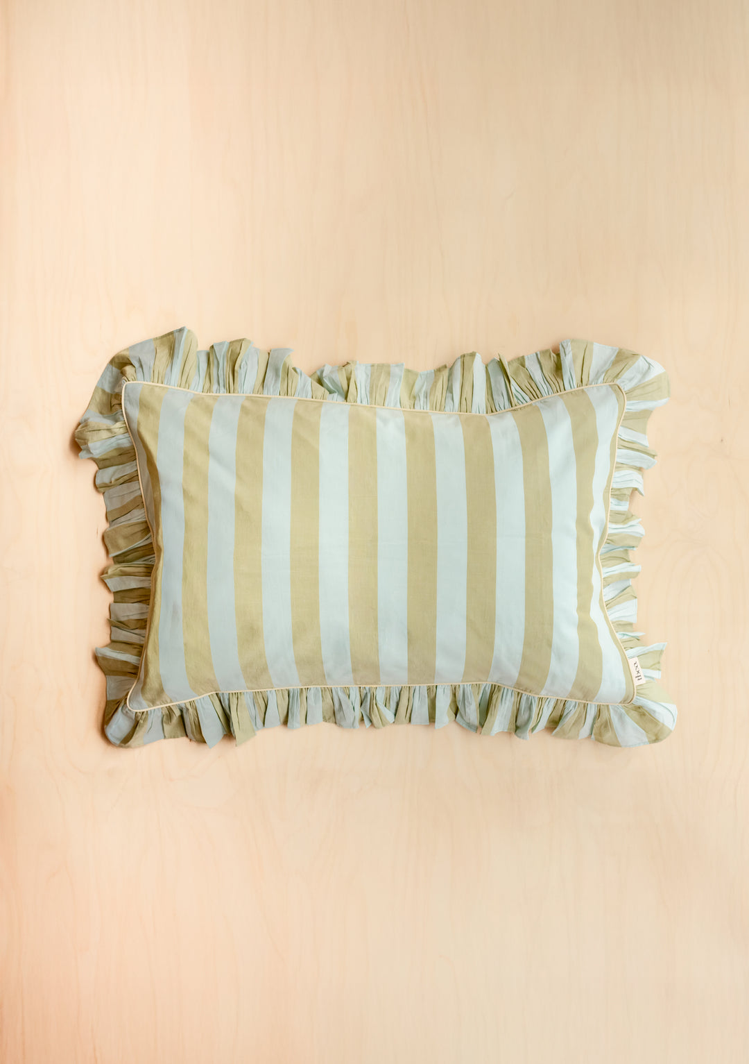 Single Pair of Cotton Pillowcases in Mint Stripe by TBCo with ruffled edge on pale wood background