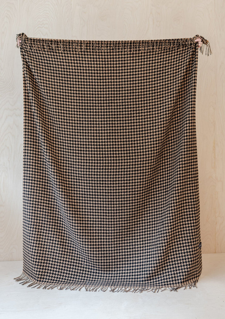 TBCo Lambswool Blanket in Camel Houndstooth pattern with fringed edges, displayed flat against light wooden background