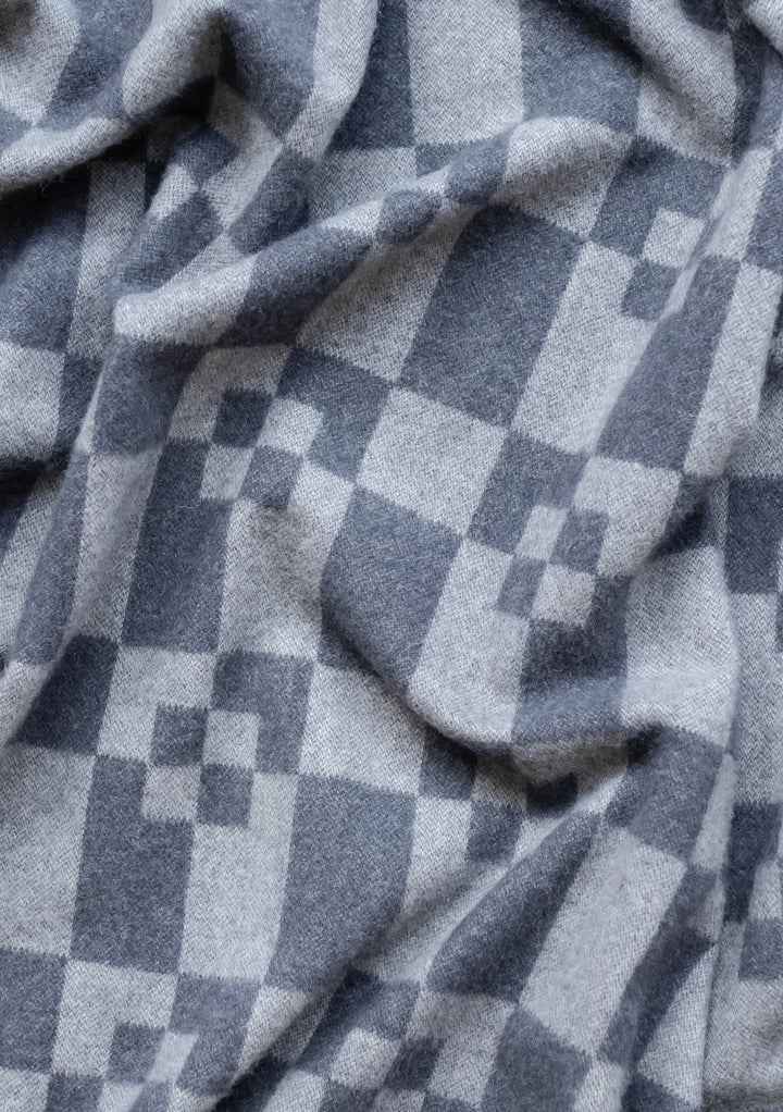 Luxurious TBCo grey geometric block cashmere and merino wool blanket with soft draping folds showing textured pattern detail