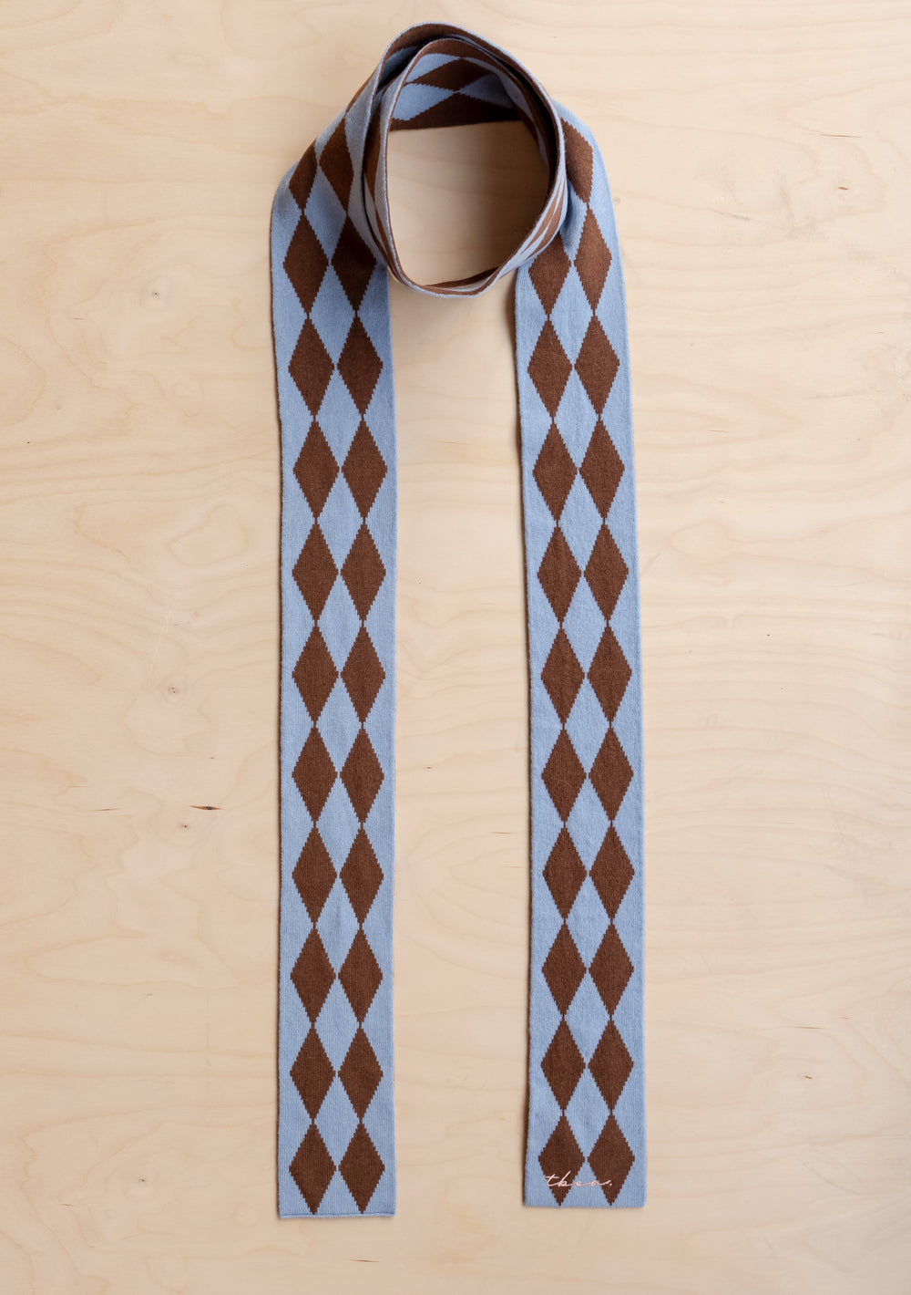 TBCo Merino Wool Skinny Scarf in Brown Harlequin with blue and brown diamond pattern laid flat on light wood surface