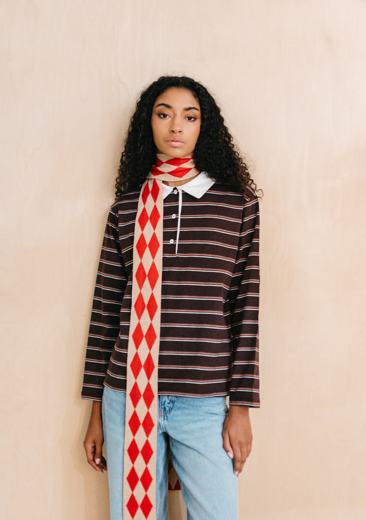 Model wearing TBCo Merino Wool Skinny Scarf in Red Harlequin with red and oatmeal diamond pattern and long slim fit