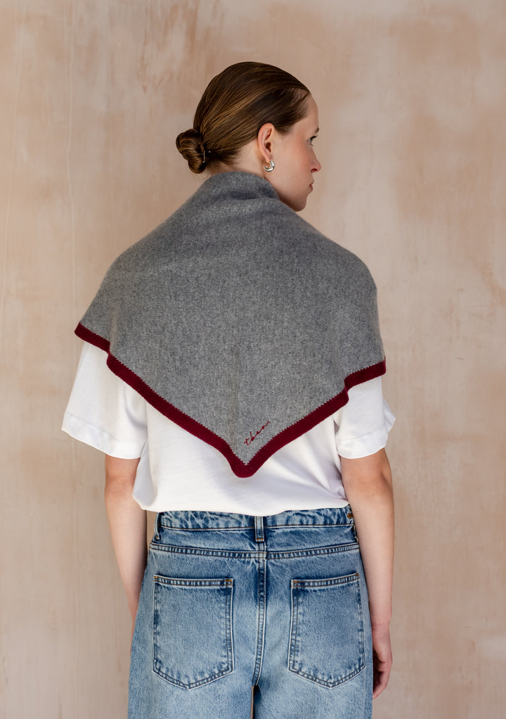 Person wearing TBCo Large Merino Wool Triangle Scarf in Charcoal & Burgundy draped over shoulders, styled with a white T-shirt and light-wash jeans, hair in low bun.