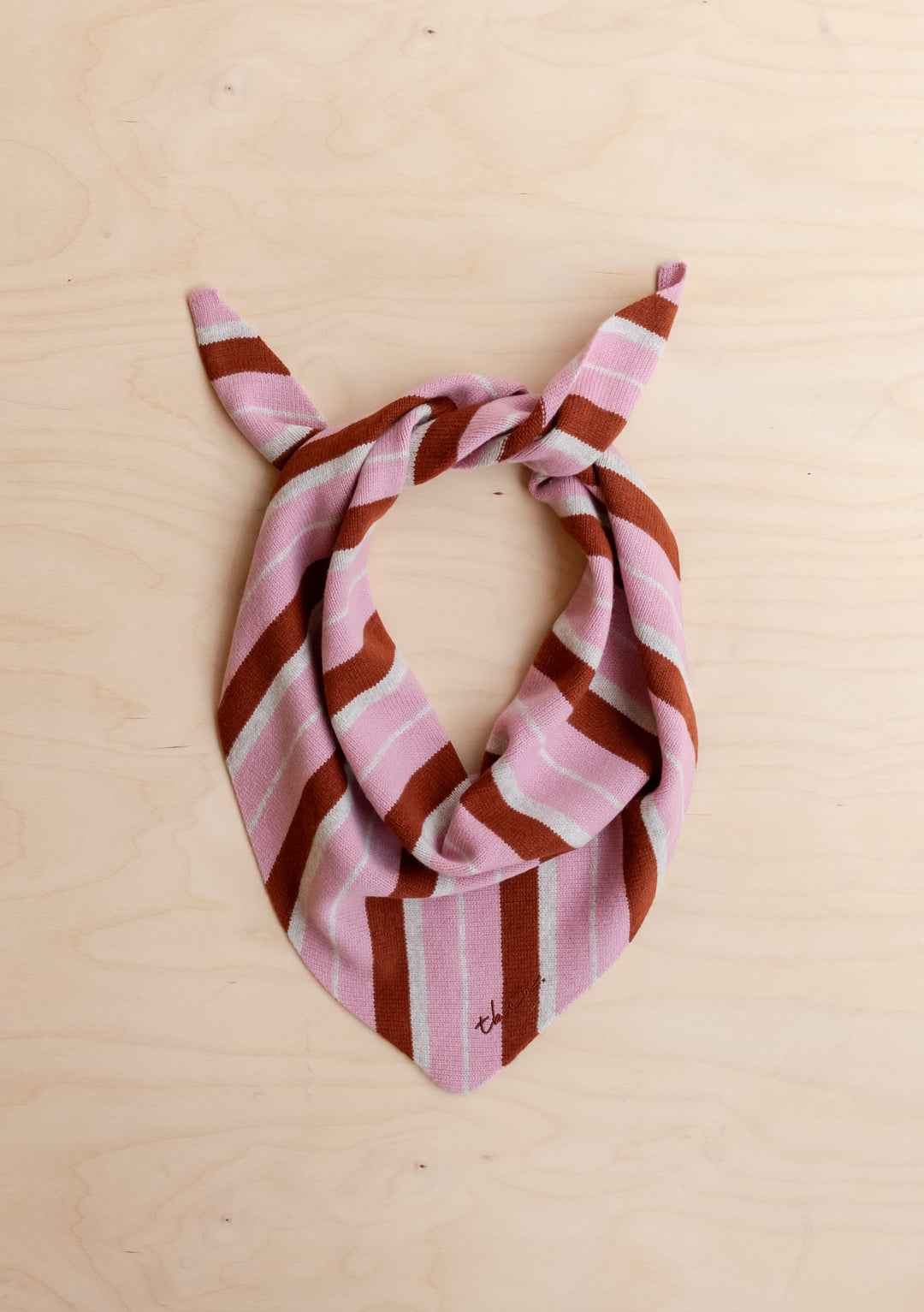 TBCo Merino Wool Triangle Scarf in Pink & Rust Stripe with bold, irregular stripes laid flat on light wooden surface