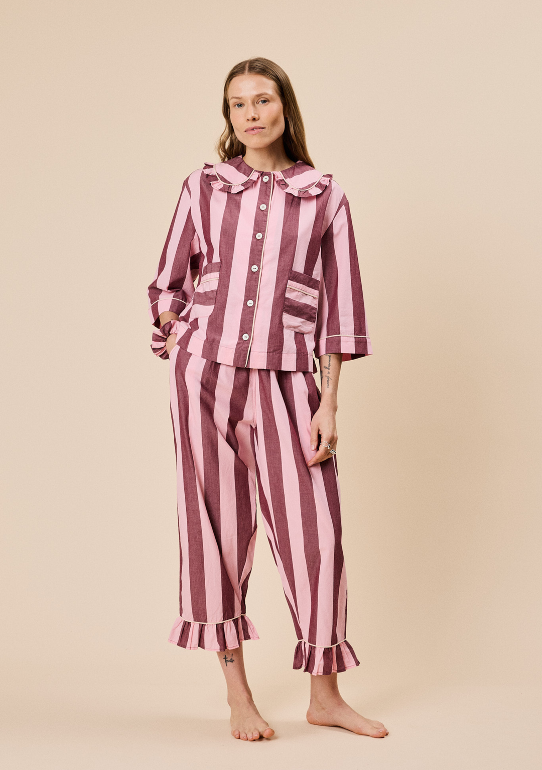 Model wearing TBCo Cropped Cotton Pyjamas in Pink & Burgundy Stripe with button-front and ruffled collar detail