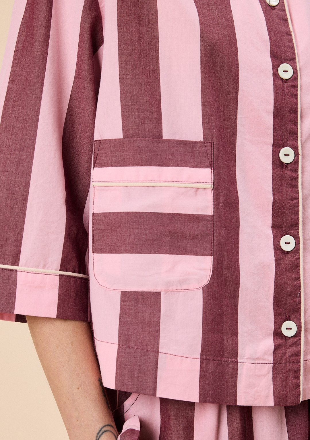Detailed close-up of TBCo Cropped Cotton Pyjamas in Pink & Burgundy Stripe showing pocket and button details with piped trim