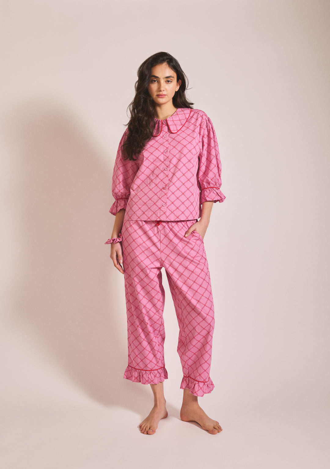 Model wearing TBCo Cropped Cotton Pyjamas in Pink Lattice with frilled cuffs, portrait orientation, gallery image one