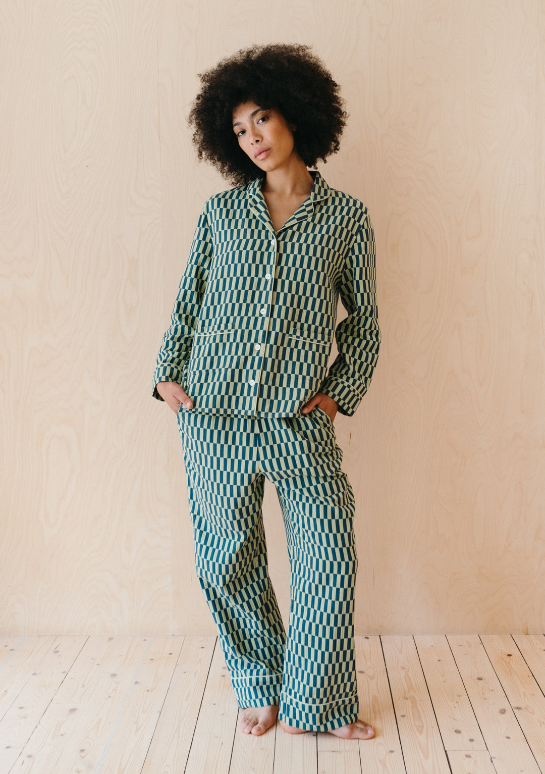 Person wearing TBCo Cotton Pyjamas in Green Checkerboard featuring geometric print and relaxed fit against beige wall