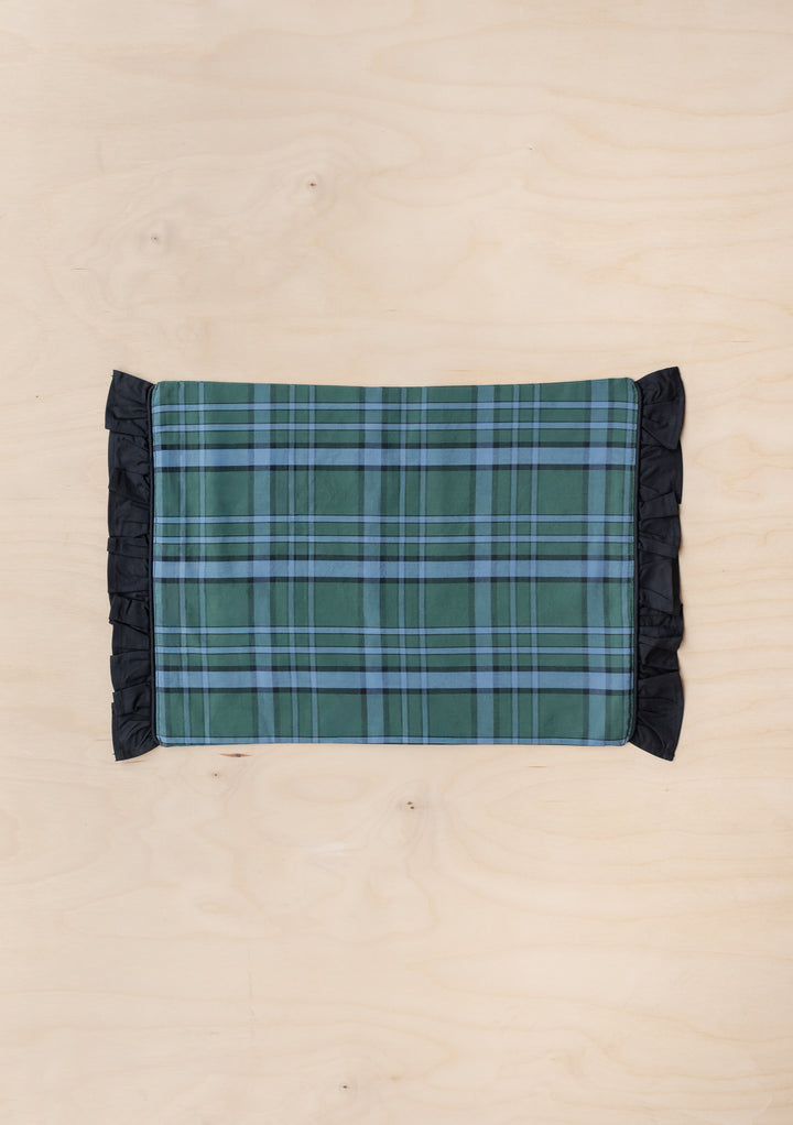Cotton Placemats Set of 2 in Green Tartan by TBCo with ruffled black edges on a light wood surface