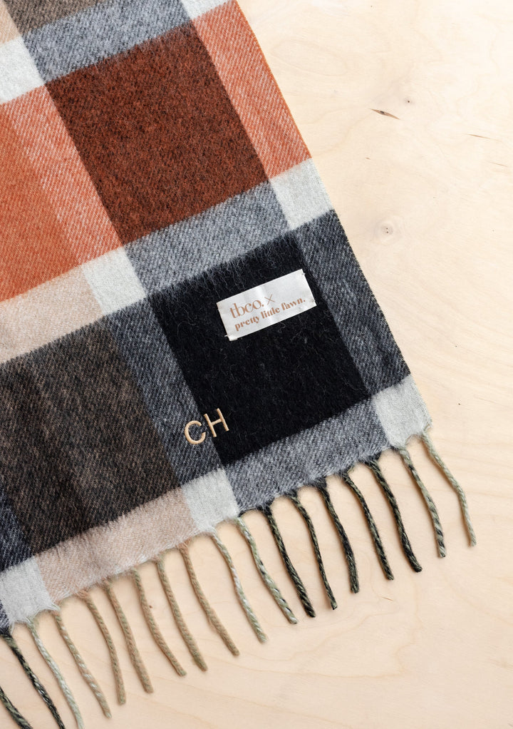 TBCo x Pretty Little Fawn Oui Scarf in plaid pattern with grey, rust and white checks, featuring tasseled fringe and label detail