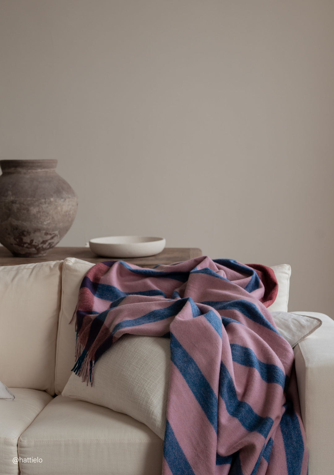 Recycled Wool Blanket in Berry Frame Stripe by TBCo draped over a cream sofa in portrait gallery position two shot