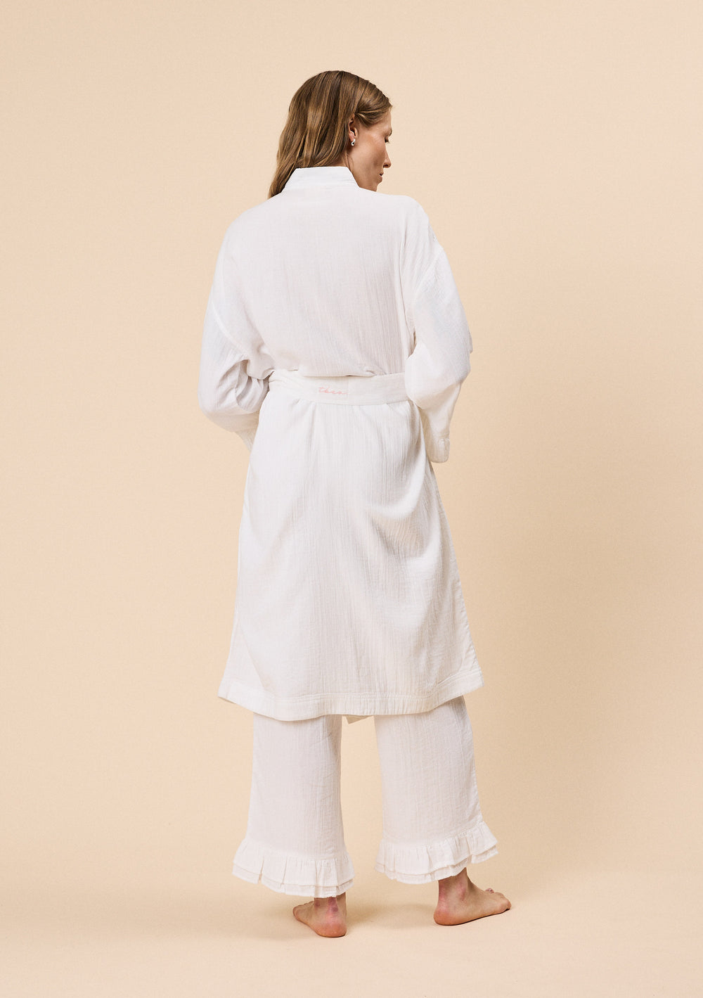 Back view of woman wearing TBCo Cotton Robe in White Ruffle with natural & recycled fibres, Certified B-Corp, women-founded, designed to make an impact