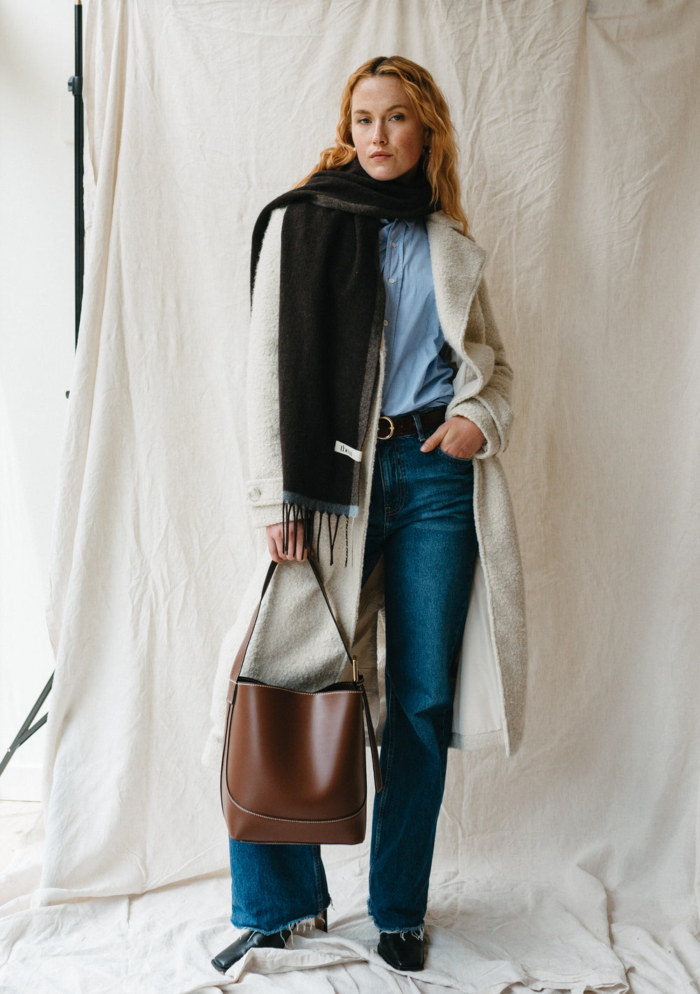 Stylish TBCo Cashmere & Merino Scarf in Brown Contrast Edge styled with winter coat, denim and leather bag against white backdrop