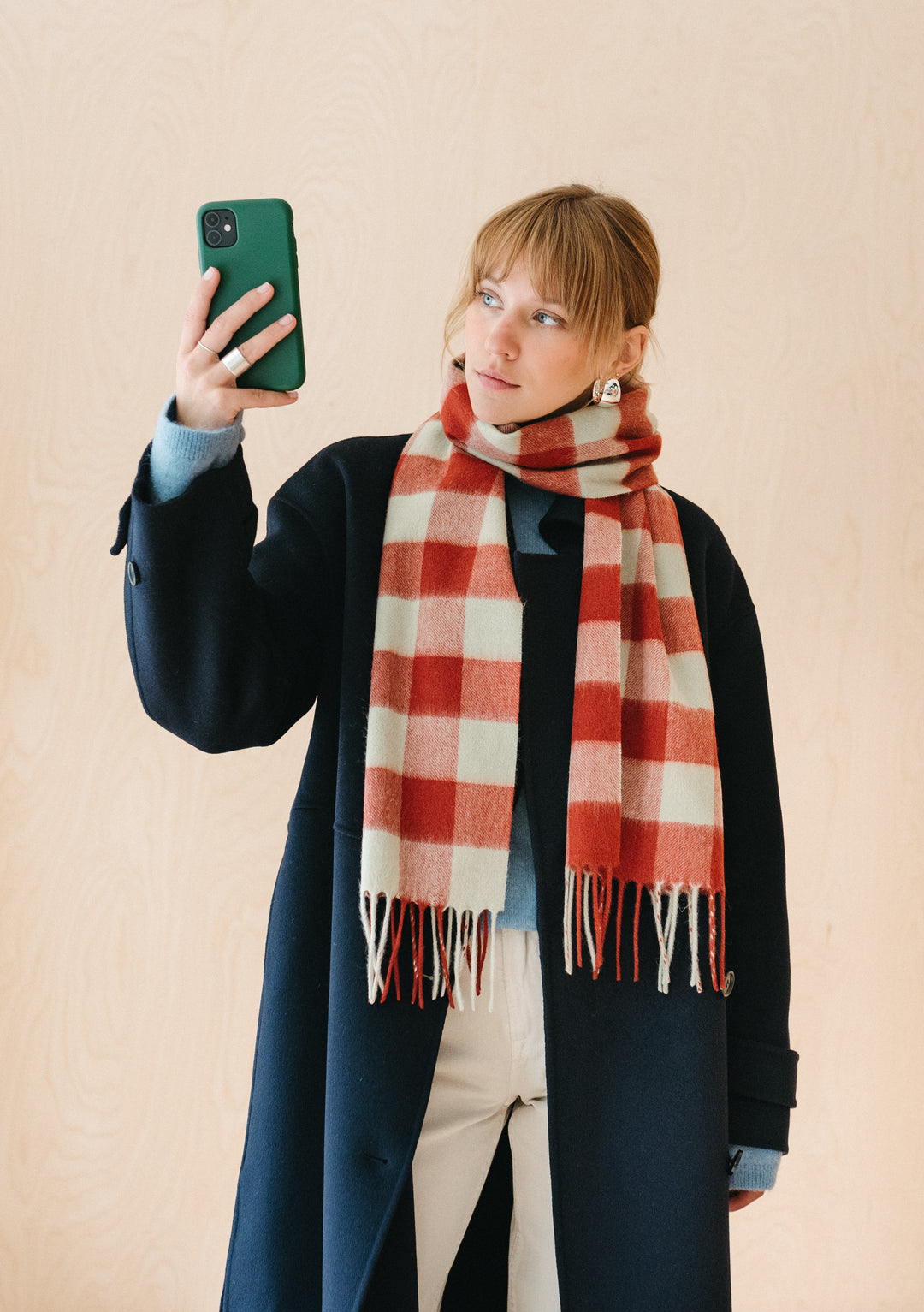 TBCo Lambswool Scarf in Red Gingham displayed in red and sage green check pattern with fringed ends against a beige background