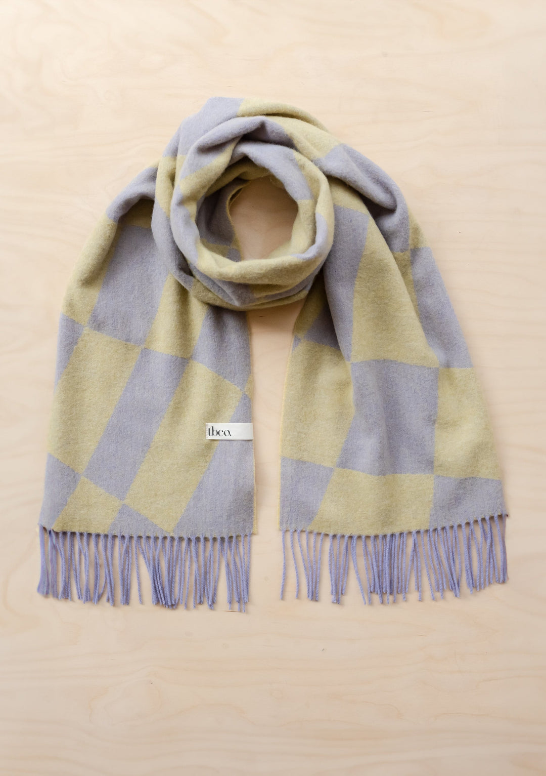 TBCo Lambswool Oversized Scarf in lavender and green organic jacquard pattern with fringe detail, displayed flat on beige surface