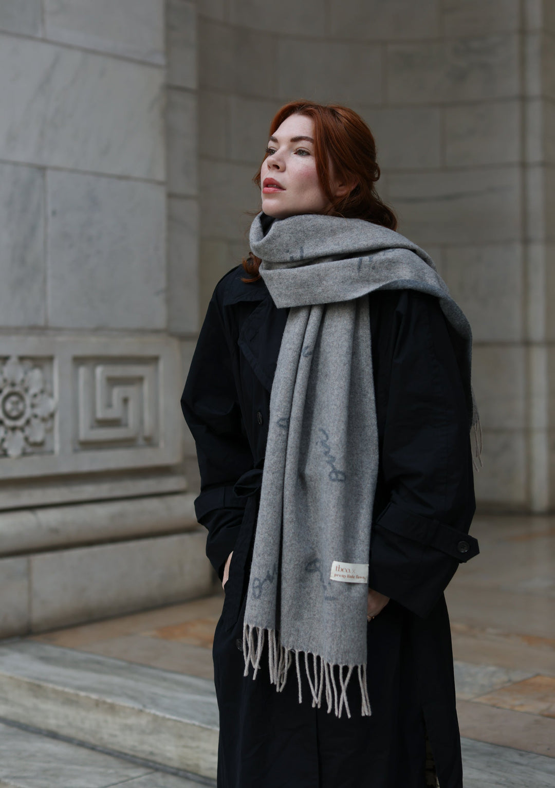TBCo x Pretty Little Fawn Oui Scarf in grey lambswool styled with black winter coat against classic stone architecture