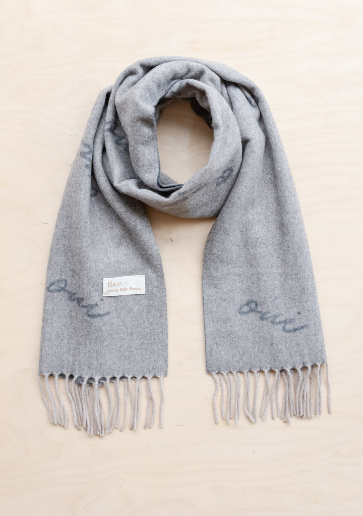 TBCo x Pretty Little Fawn Oui Scarf in soft grey lambswool with fringed edges and embroidered text detail, displayed flat