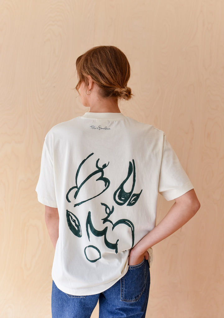 Woman seen from behind wearing The Artist Series TBCo x Simone Brewster Cotton T-Shirt with abstract black shapes on back