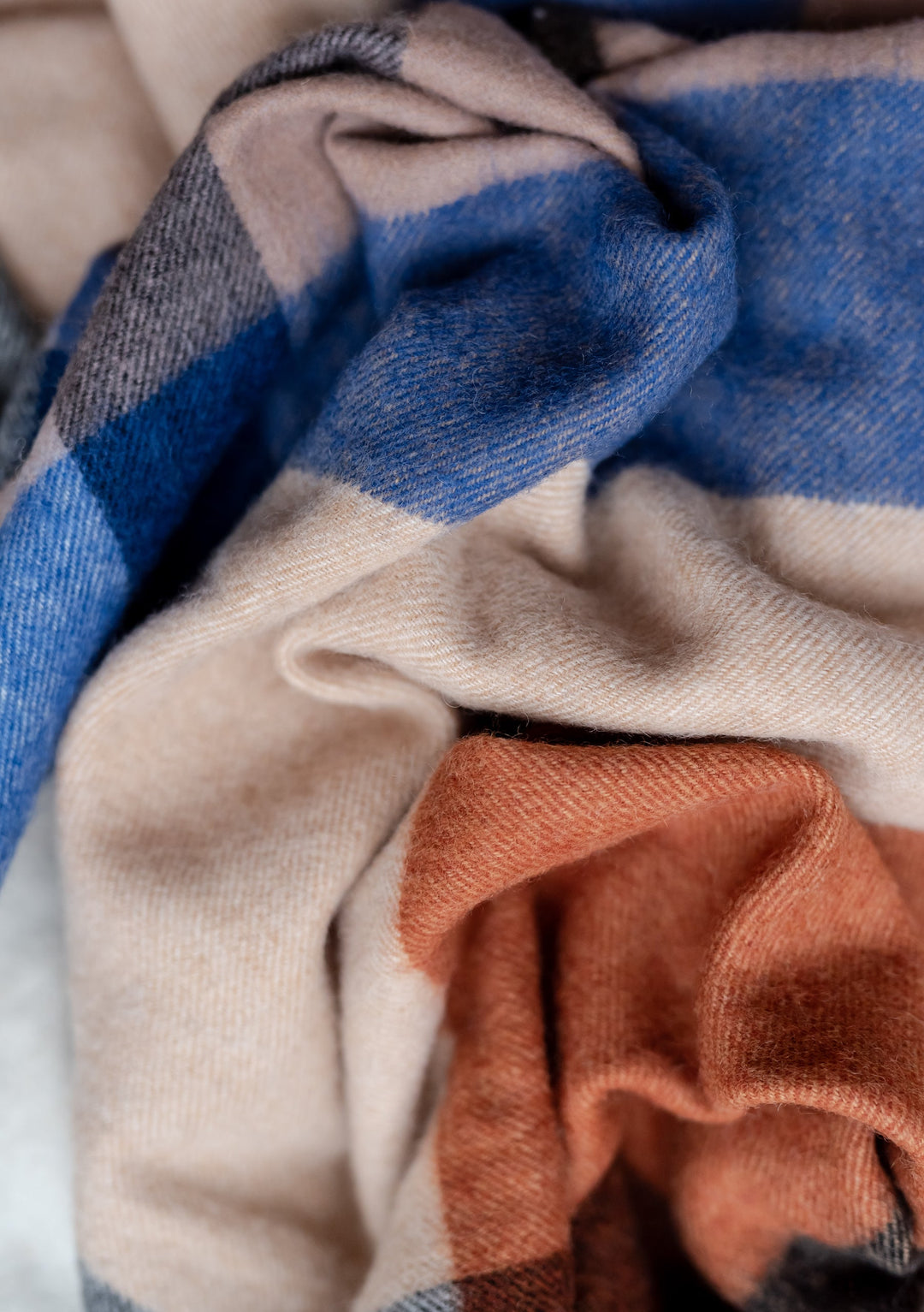 TBCo Lambswool Blanket Scarf in Camel Modern Check featuring soft folds of blue, beige and umber wool in closeup texture detail