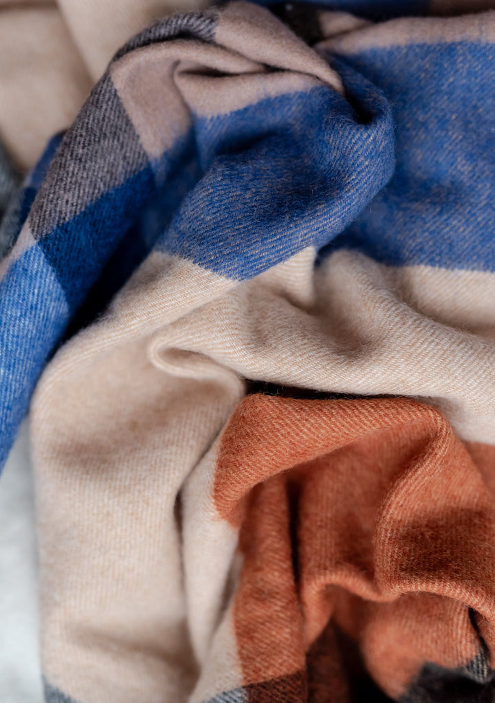 TBCo Lambswool Blanket Scarf in Camel Modern Check featuring soft folds of blue, beige and umber wool in closeup texture detail
