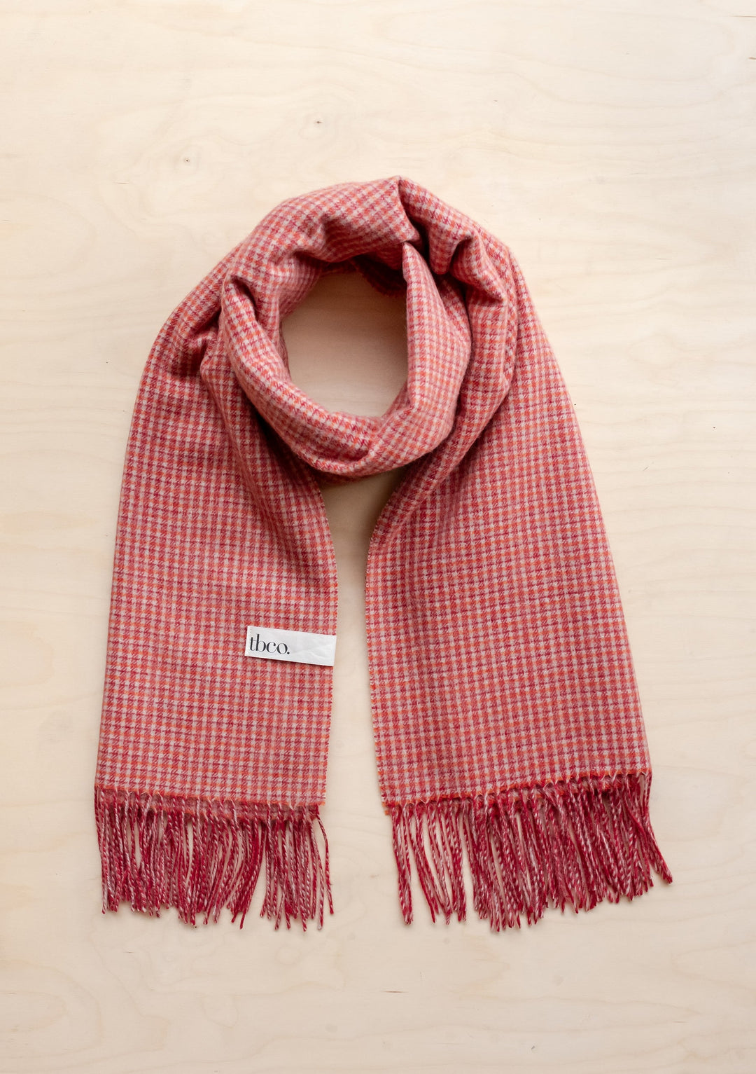 Portrait image of TBCo Sample Sale Lambswool Blanket Scarf in Berry Textured Check with fringed edges and visible label