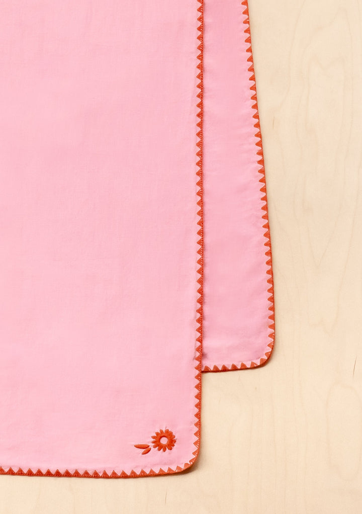TBCo Cotton & Linen Table Runner in pink with orange embroidered edges and floral detail, photographed on beige surface