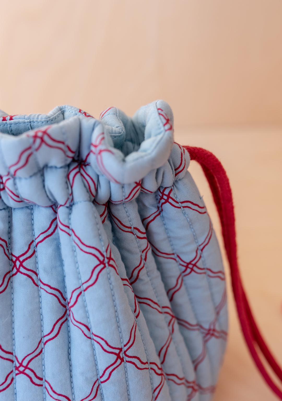 Close-up portrait of the Cotton Wash Bag in Blue Lattice by TBCo showing red lattice pattern and drawstring closure